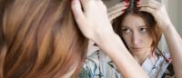 woman examining her hair in the mirror